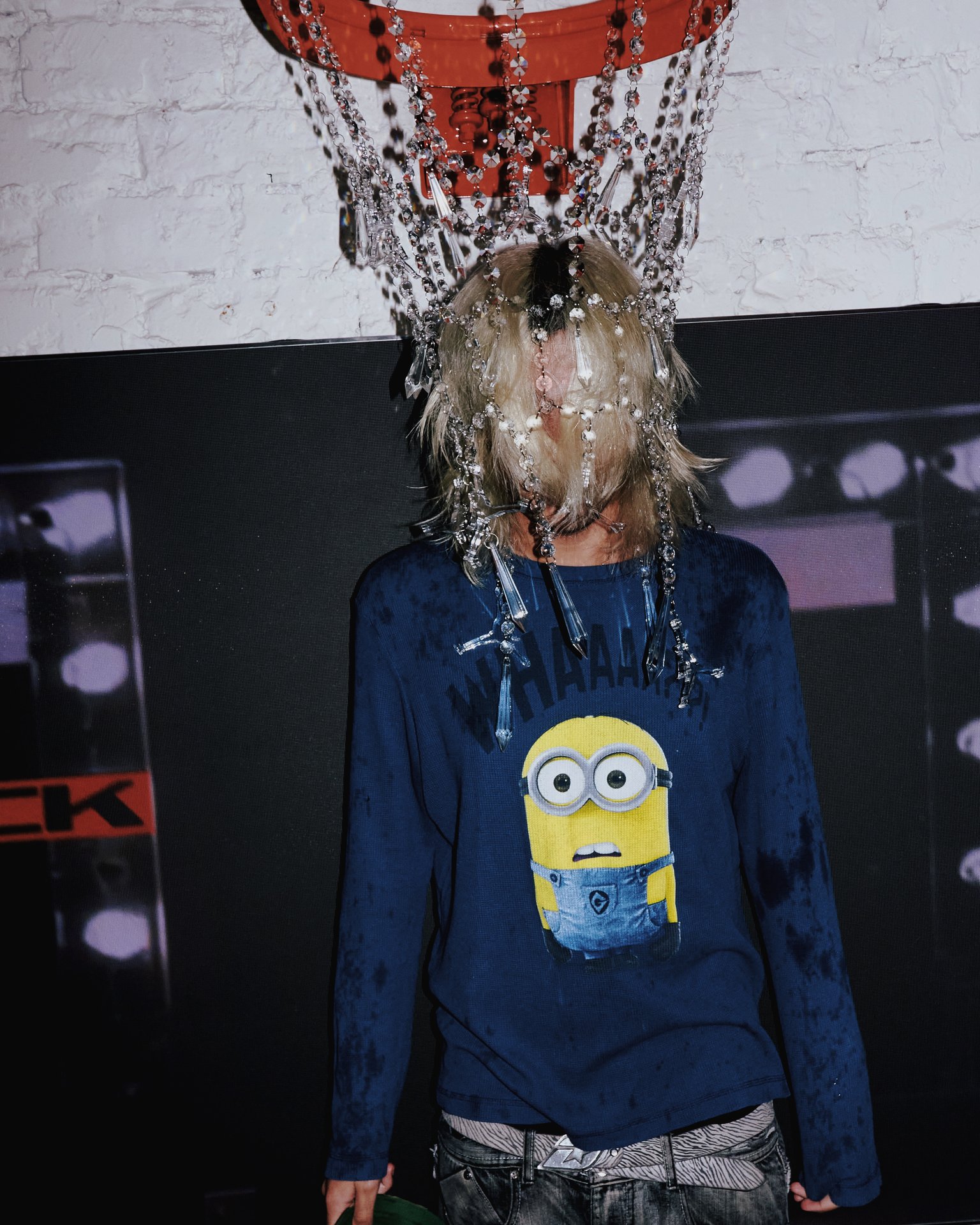 Performer in a Minion shirt wearing crystal chains beneath the crystal basketball hoop