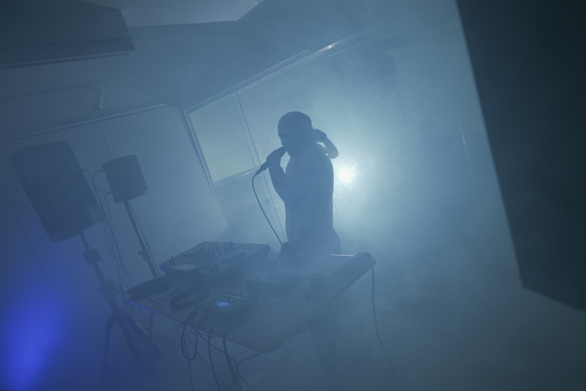 Holy Yam’s silhouette rapping into a microphone through stage smoke
