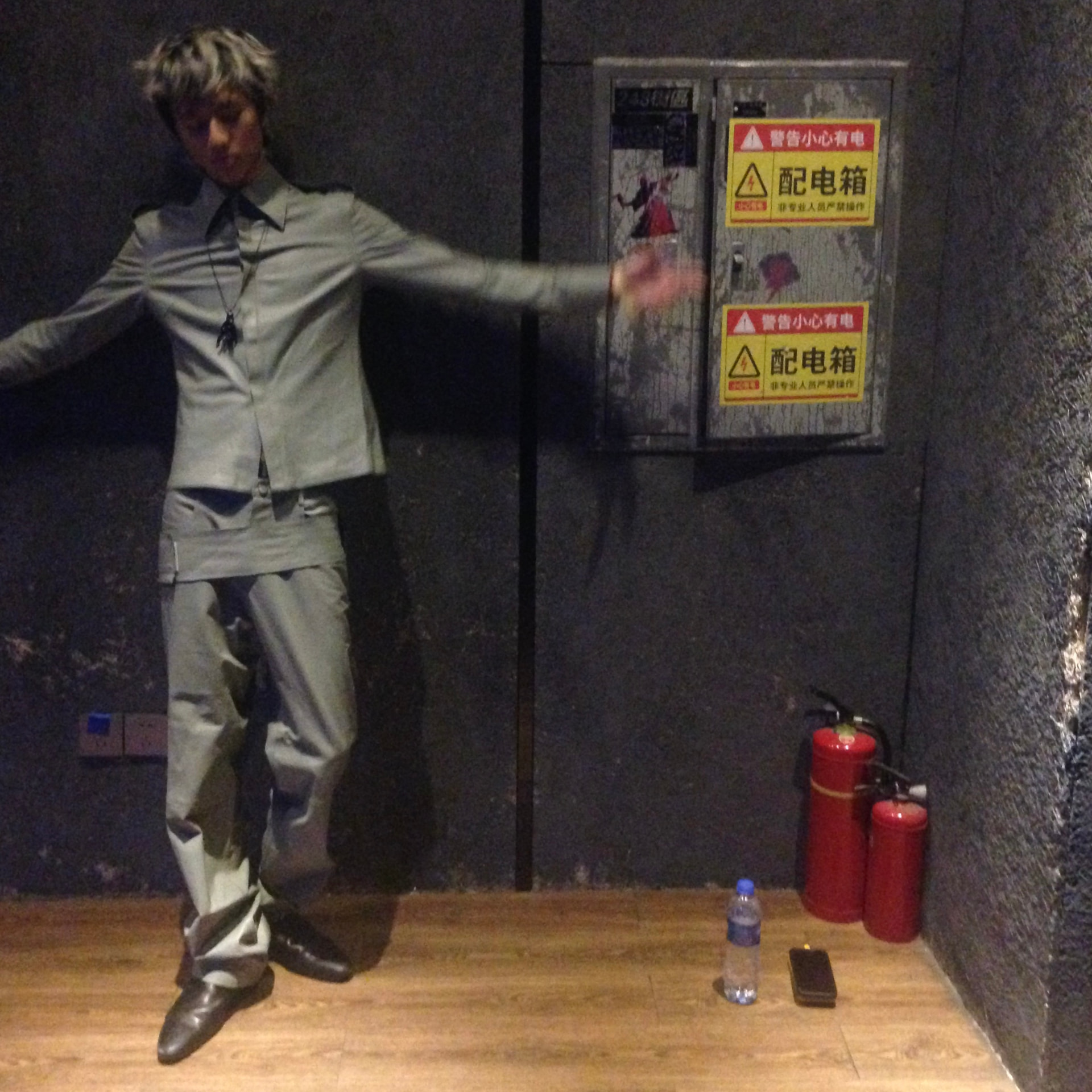 Lan with arms outstretched against a dark backstage wall