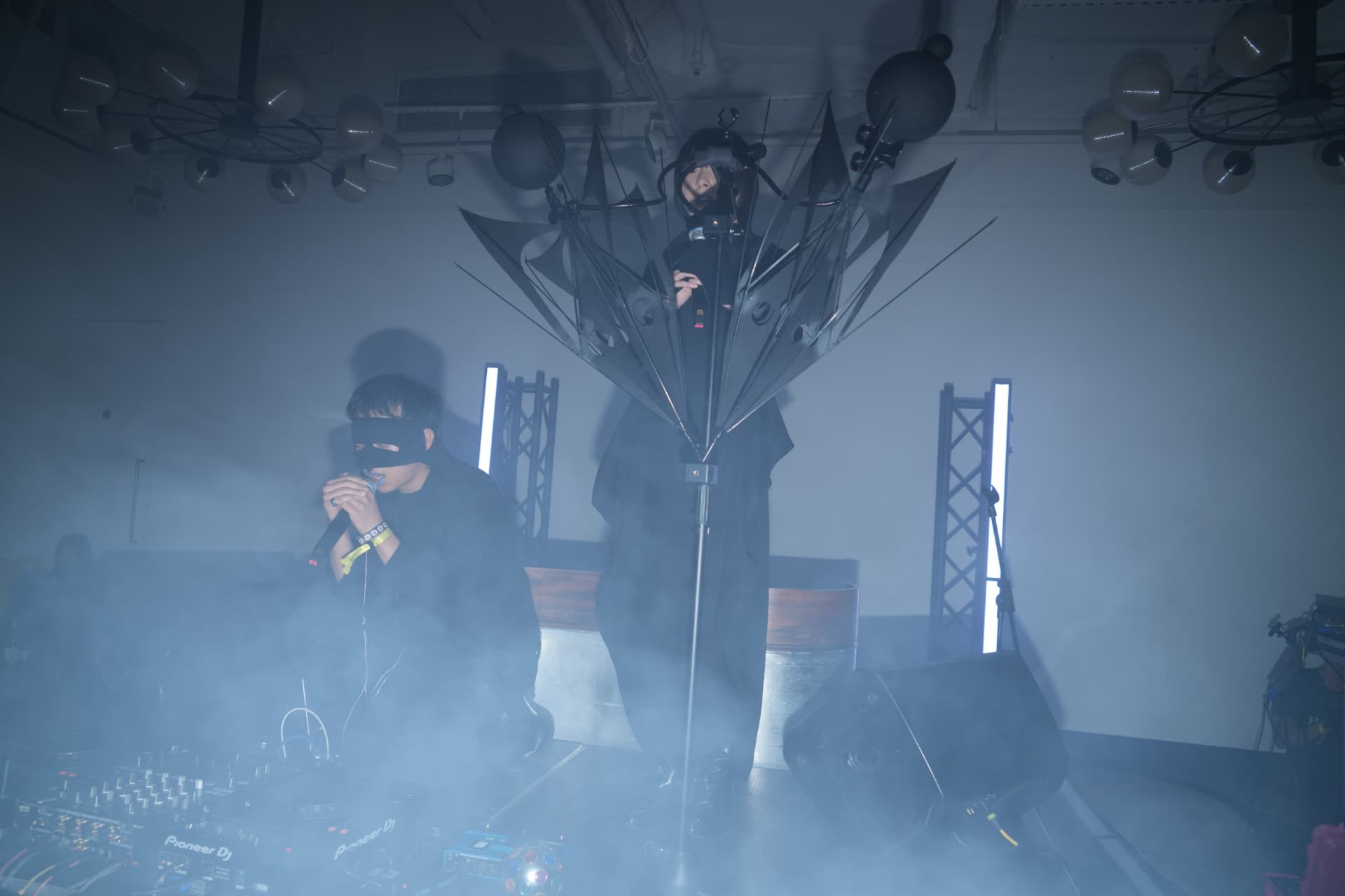 Holy Yam performing live with an umbrella sculpture and haze